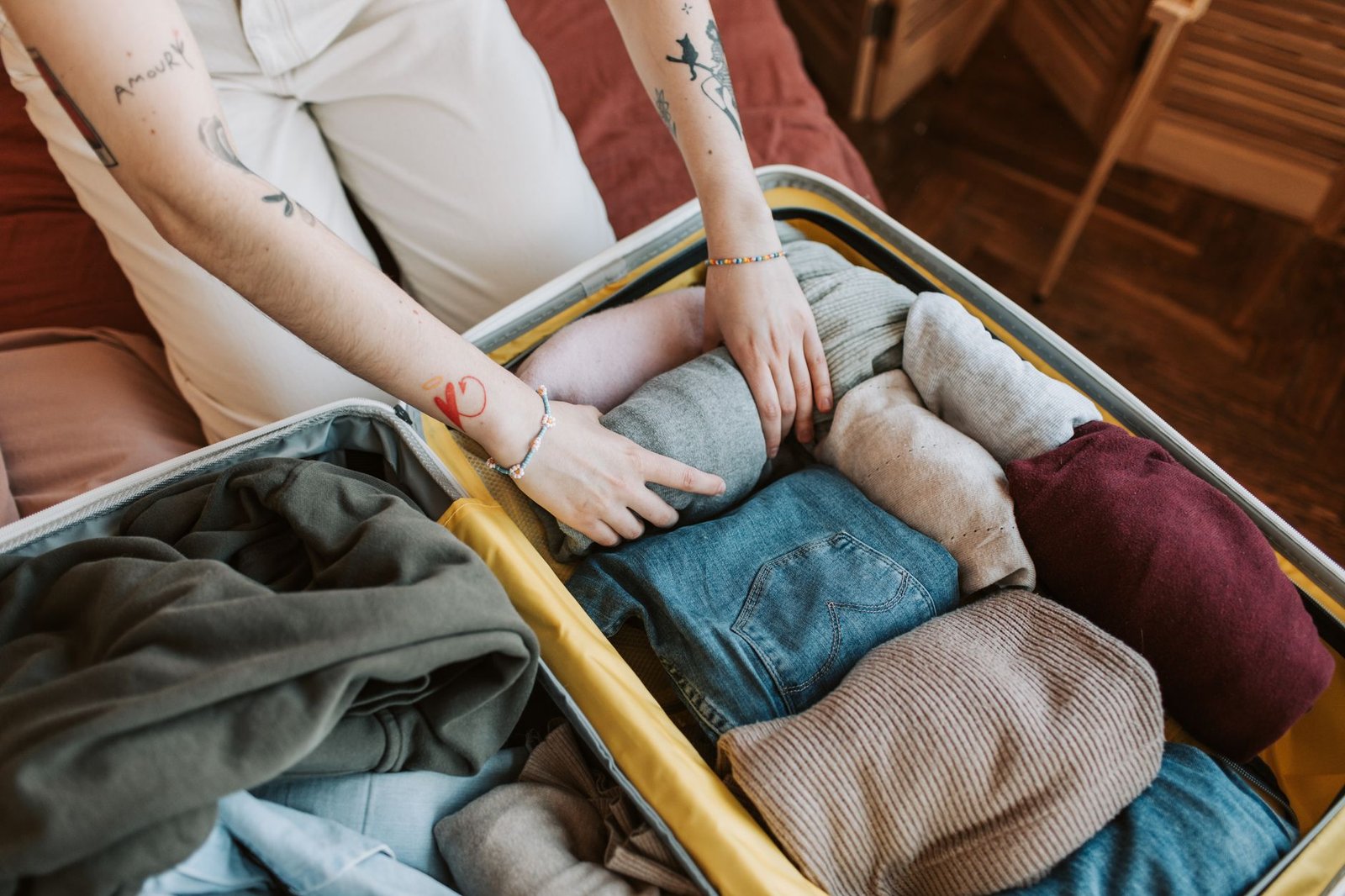 Hands arranging breathable heat-ready layers in travel suitcase