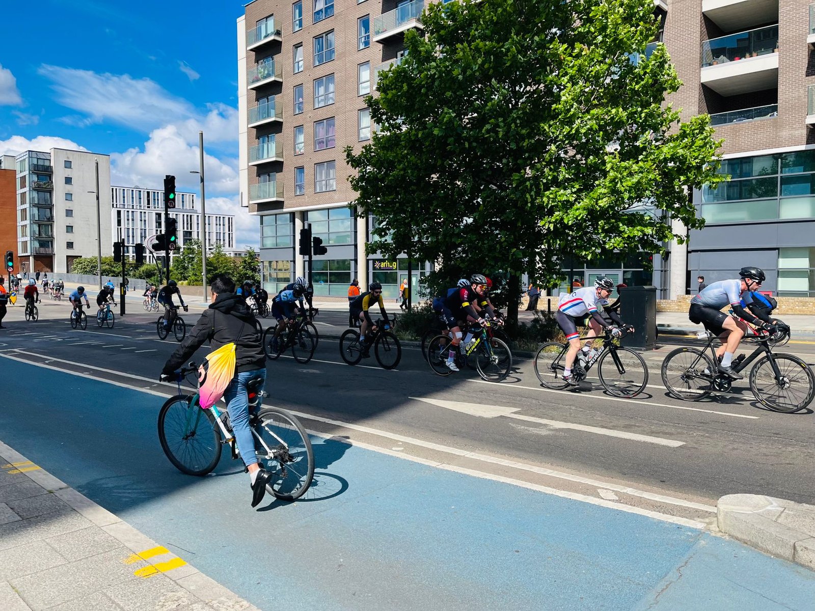 Cyclist adjusting gear layers amid London sun and clouds